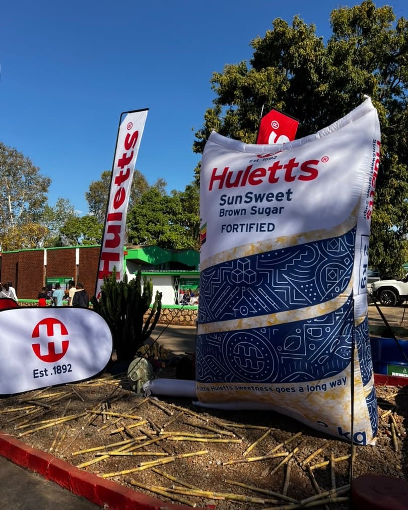 A giant inflatable Huletts SunSweet pack standing among Huletts banners and cut cane at an exhibition stand